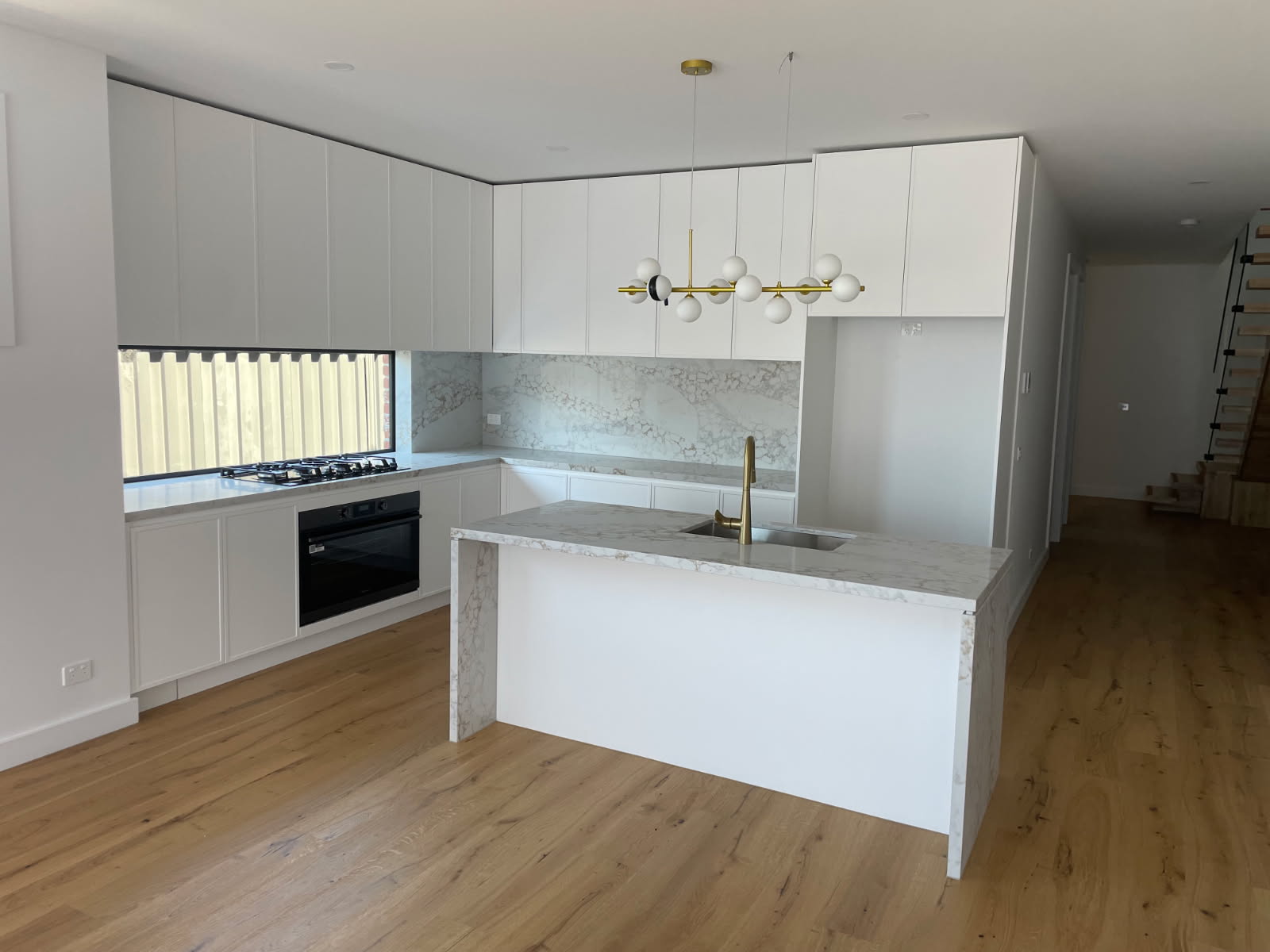 L-shaped white shaker kitchen with marble splashback